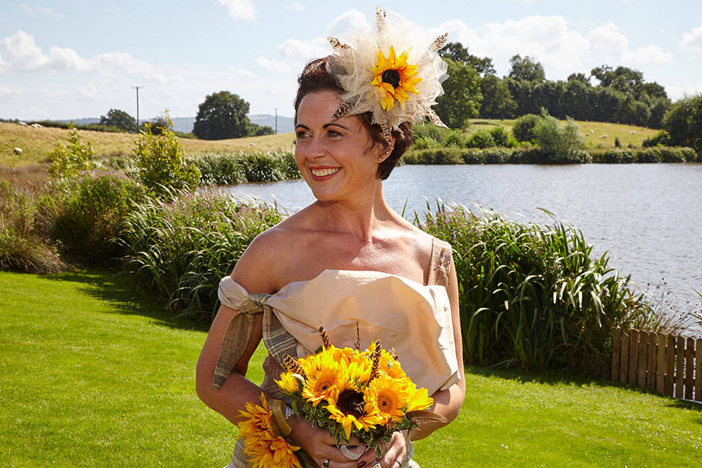 Bride wearing cream dress with sunflower bouquet