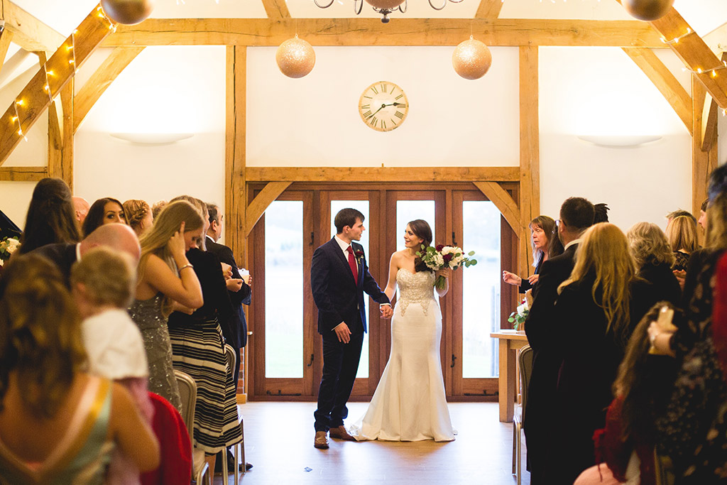 Bride and groom holding hands at the end of the aisle
