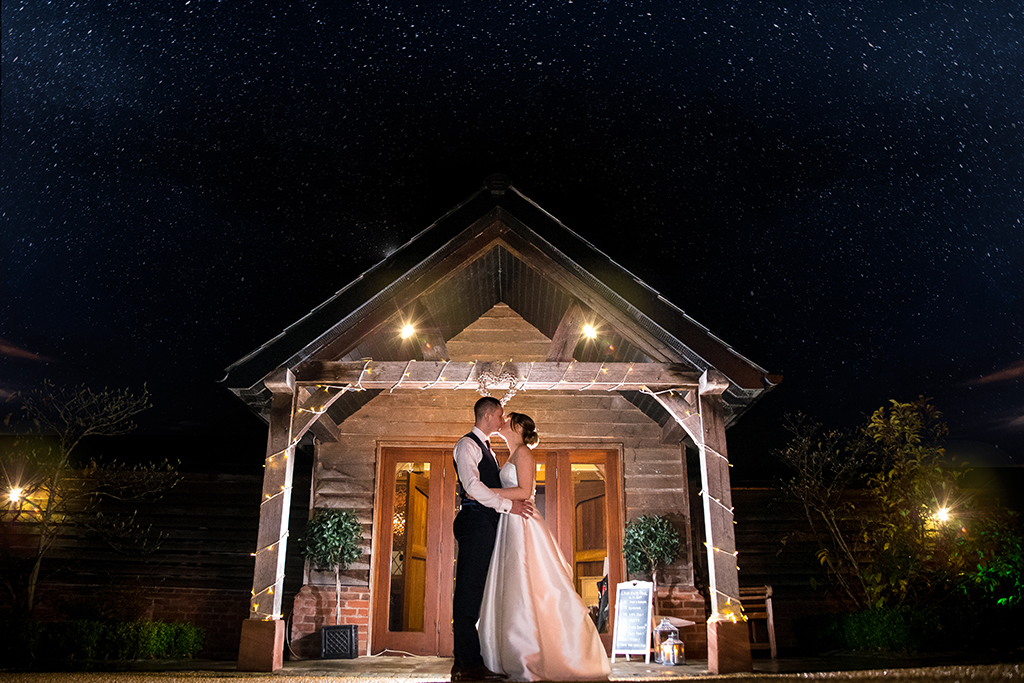 The happy couple pose for a wedding photo on a snowy evening at this wedding venue in Cheshire