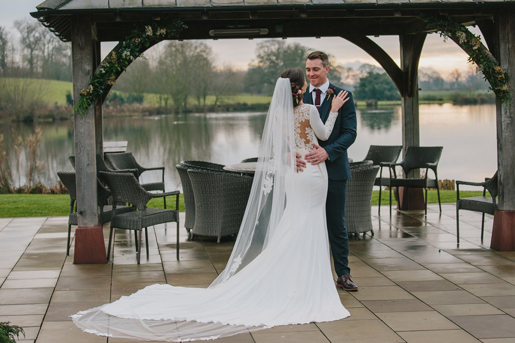 The happy newlyweds pose for a photo by the Clock tower at this lakeside wedding venue near Manchester