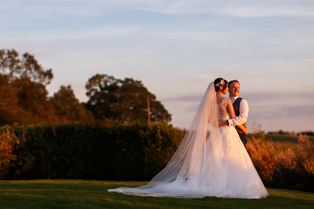 The happy couple pose for wedding photos in the gardens at Sandhole Oak Barn near Manchester