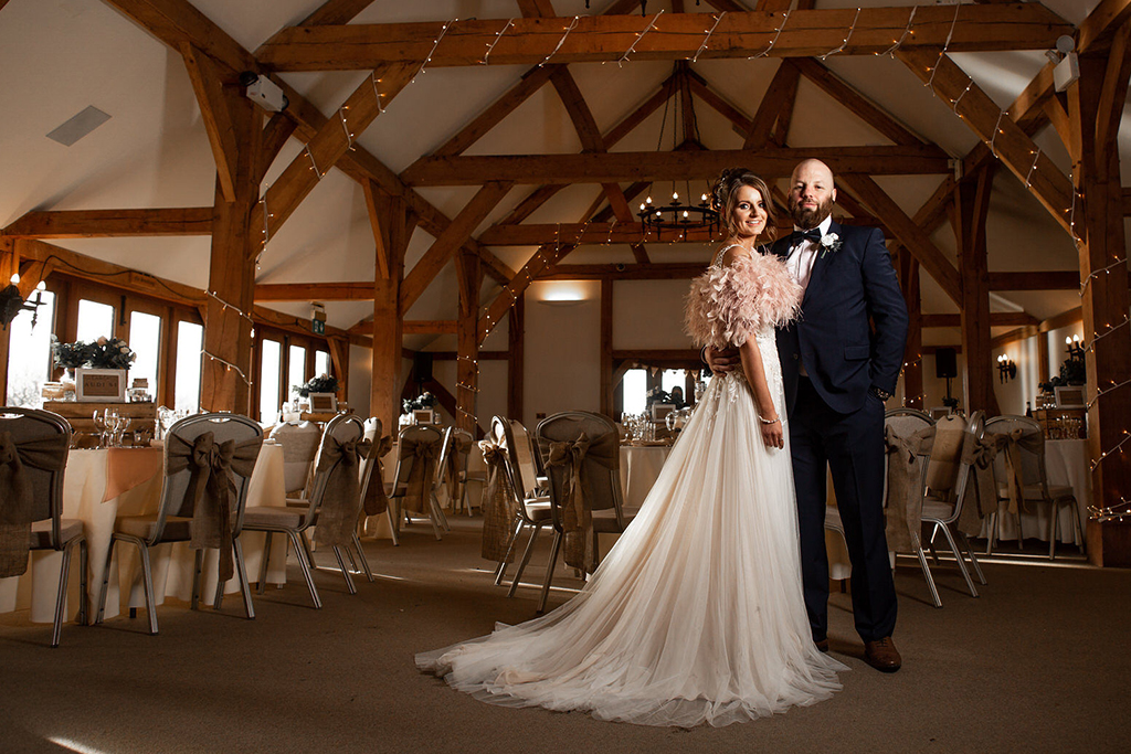 The happy couple pose for a wedding photo in the Oak Barn at Sandhole in Cheshire