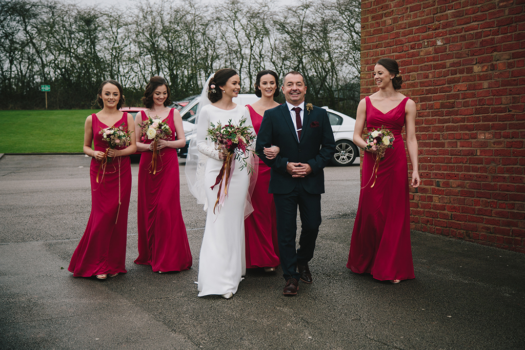 The bride wore a stunning sleeved bridal gown with a veil and her bridesmaids wore deep pink dresses at this barn wedding in Cheshire