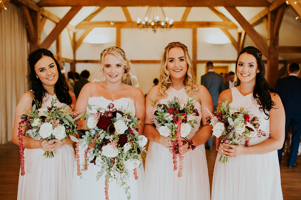 The bride stands with her bridesmaids who all wore light pink bridesmaid dresses