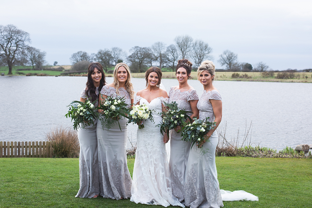 The bride wore a stunning off-the-shoulder-lace-dress while her bridesmaids wore beautiful silver dresses with lace detail at this rural barn wedding in Cheshire