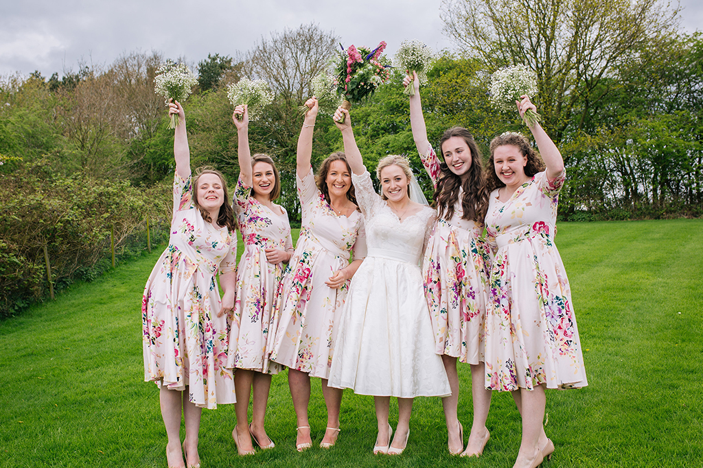The bride wore a pretty lace tea-length wedding dress while the bridesmaids wore vintage floral dresses at this rustic barn wedding