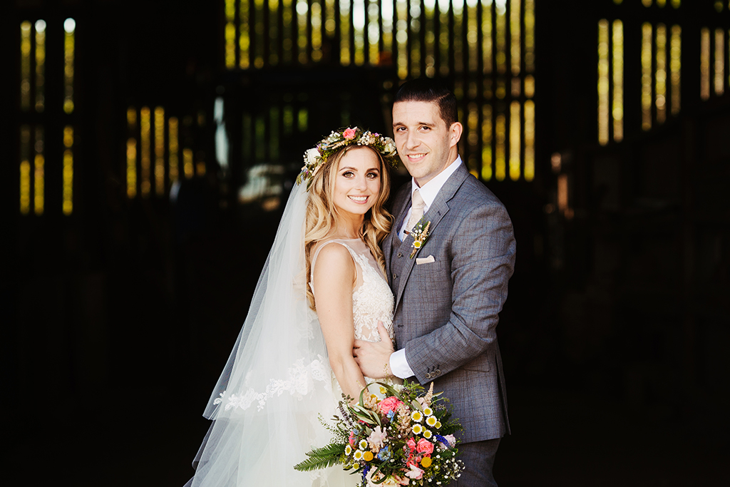 The bride and groom pose for a wedding photo in the unused barn at rural wedding venue Sandhole Oak Barn