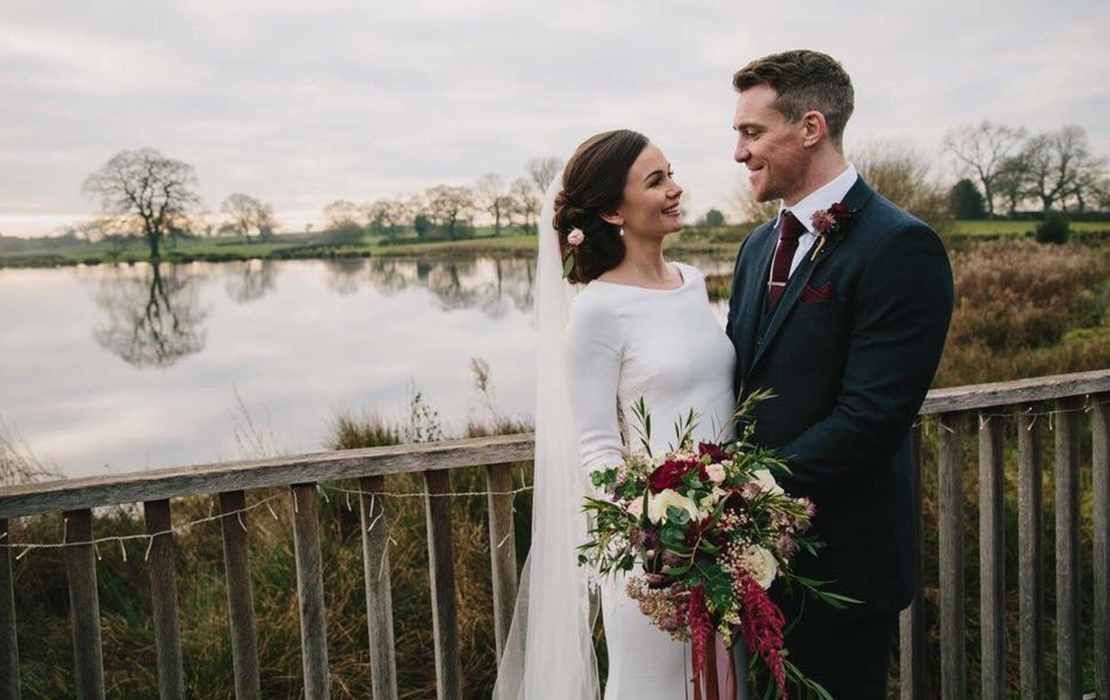 The happy couple pose for a winter wedding photo with the lake in the background at Sandhole Oak Barn