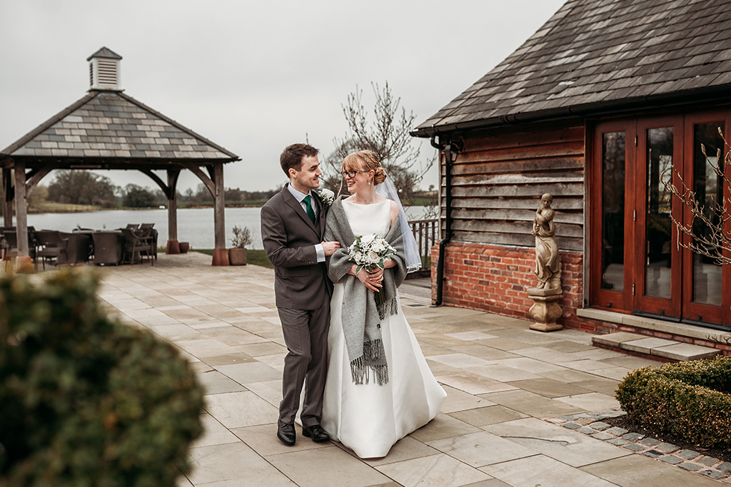 The bride and groom have some wedding photos taken outside the barn at their spring barn wedding in Cheshire