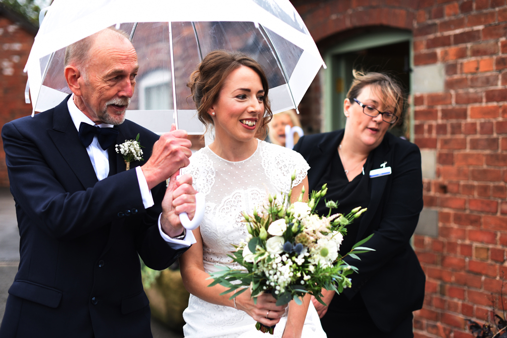The happy bride walks to the wedding ceremony at Sandhole Oak In Cheshire