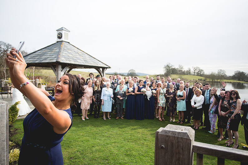 Bridesmaid in navy dress taking a group selfie