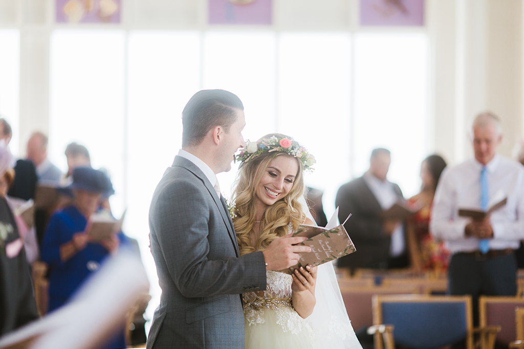 The happy bride and groom sing hymns at their wedding ceremony before celebrating at Sandhole Oak Barn in Cheshire