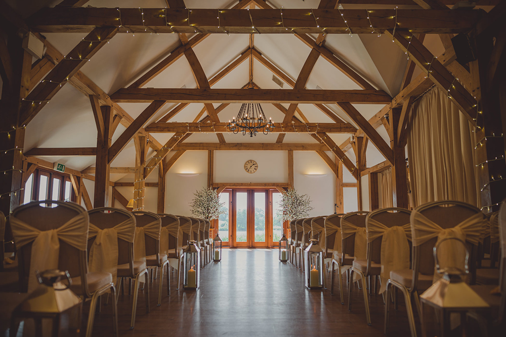 The barn was set up for the wedding ceremony with pretty fairy lights around the beams and lanterns down the aisle