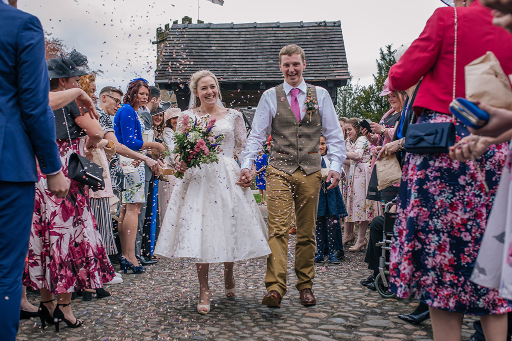 The happy newlyweds have confetti thrown over them at their Cheshire wedding