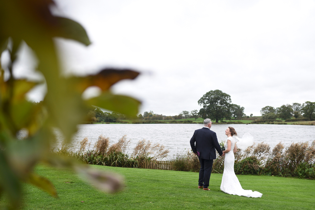 The happy couple take a stroll alongside the lake at this waterside wedding venue in Cheshire