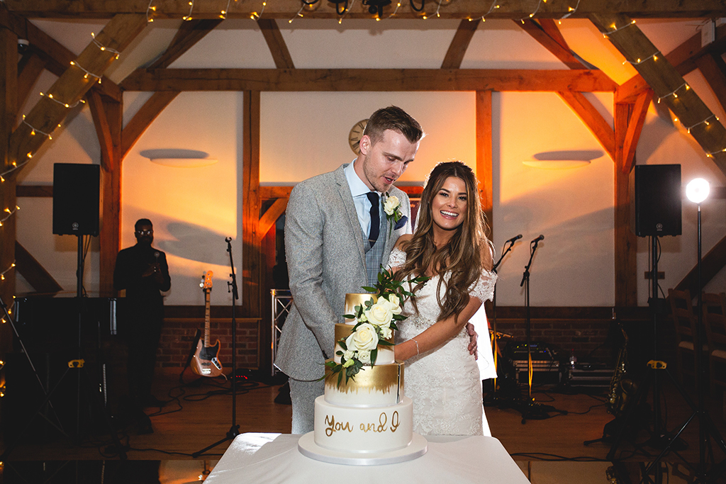 The four tier wedding cake was iced with white fondant and sprayed with gold at this spring barn wedding at Sandhole Oak Barn
