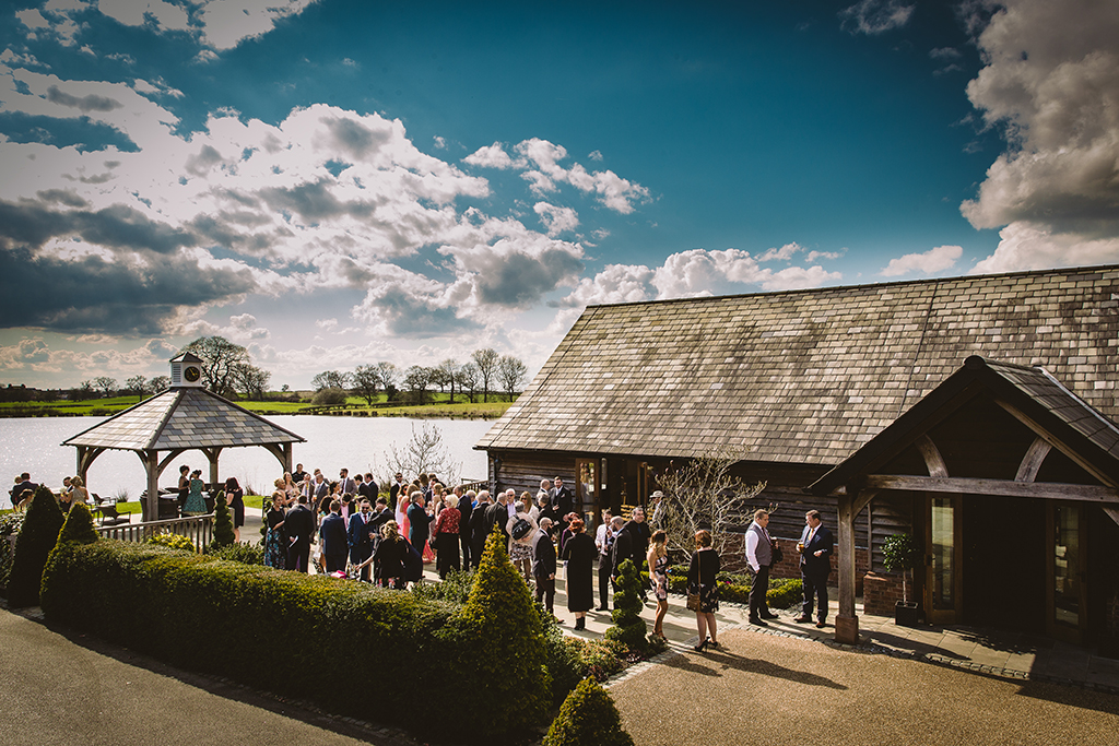 The wedding guests enjoy the reception drinks in the sun at this barn wedding in Cheshire