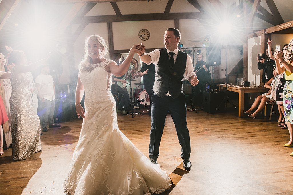The excited bride and groom enjoy their first dance as Mr and Mrs in front of family and friends
