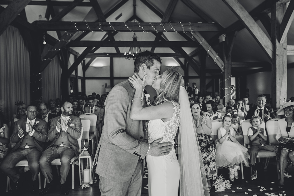 The happy newlyweds have their first kiss at their wedding ceremony at Sandhole Oak Barn 