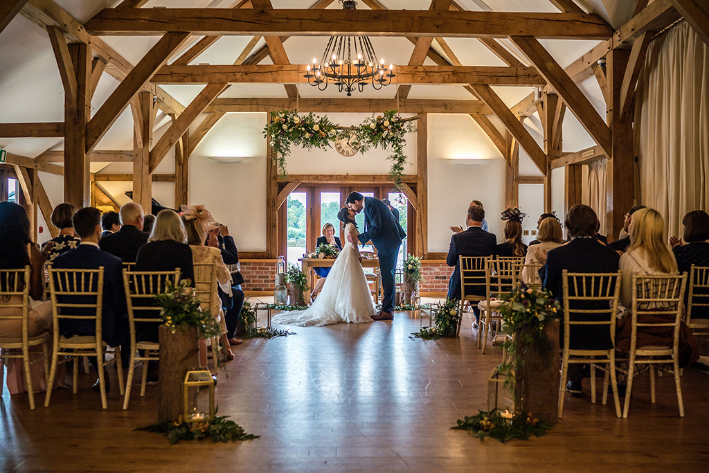 The bride and groom share their first kiss as a married couple at this barn wedding in Cheshire