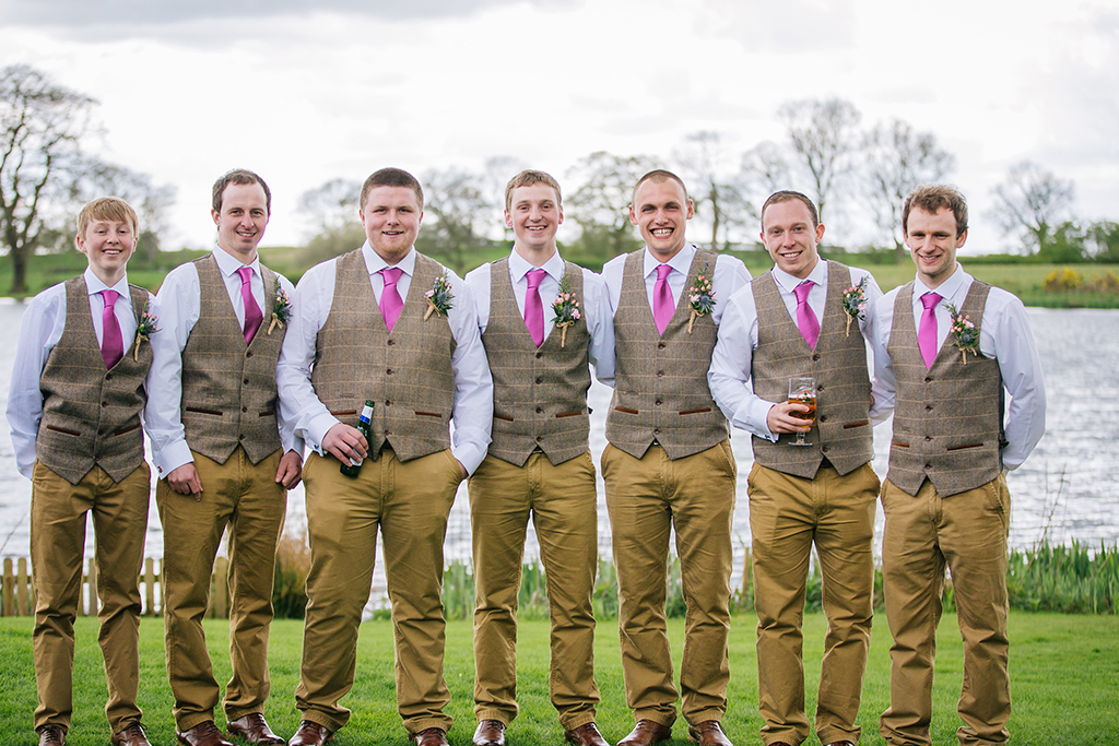 The groom and groomsmen wore country check waistcoats with beige trousers and pink ties at this rustic wedding at Sandhole Oak Barn
