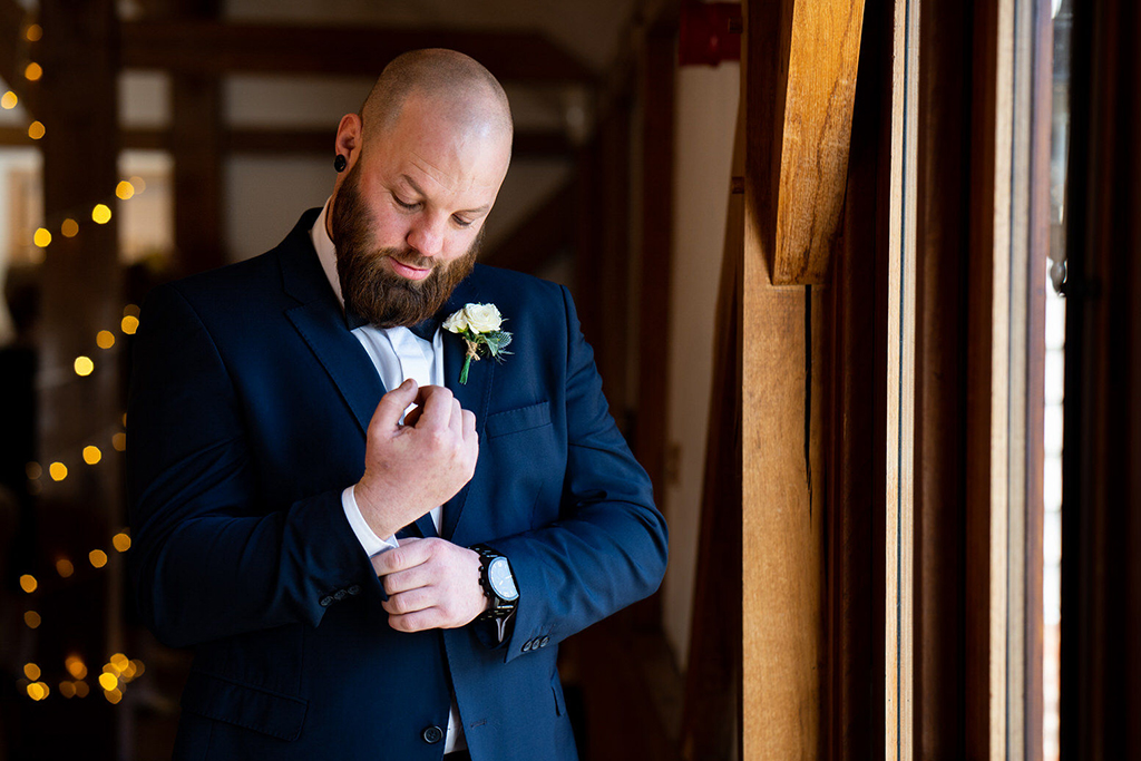 The groom makes the final touches to his outfit before the wedding ceremony at Sandhole Oak Barn