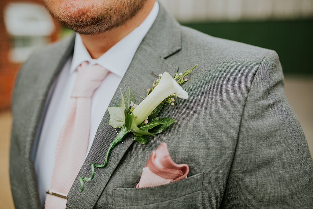 The groom wore a light grey suit with pink handkerchief and floral buttonhole