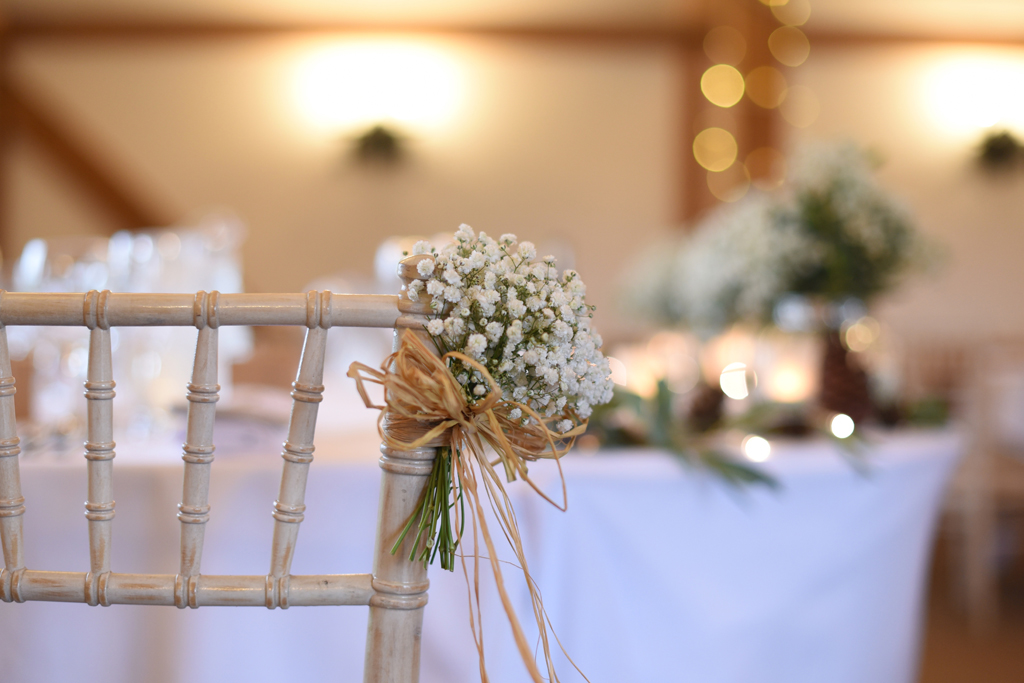 Mini bunches of gypsophila were tied to the chairs at this barn wedding in Cheshire