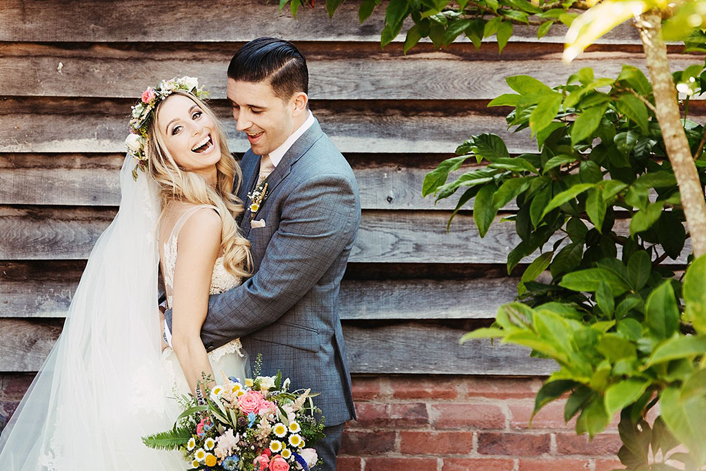 The happy newlyweds pose for a wedding photo in front of the wedding barn In Cheshire