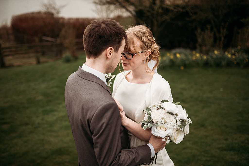 The happy couple share a moment as they pose for a wedding photo outdoors at Sandhole Oak Barn 