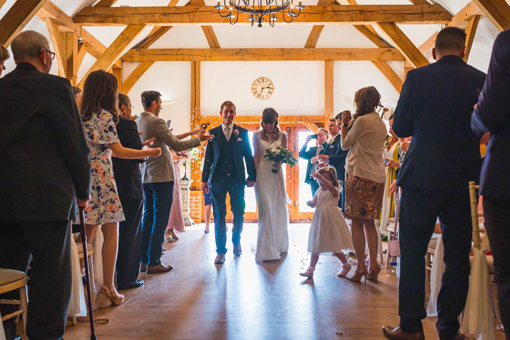 The happy newlyweds walk back down the aisle as guests throw confetti over them