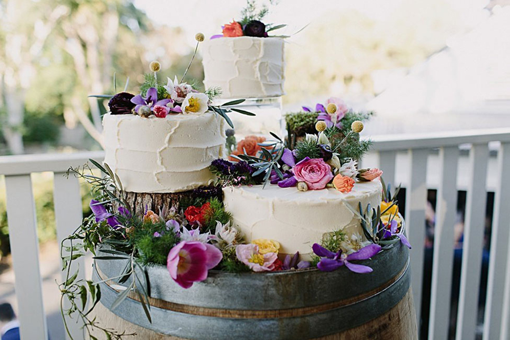 An individual tiered wedding cake decorated with lots colourful wedding flowers