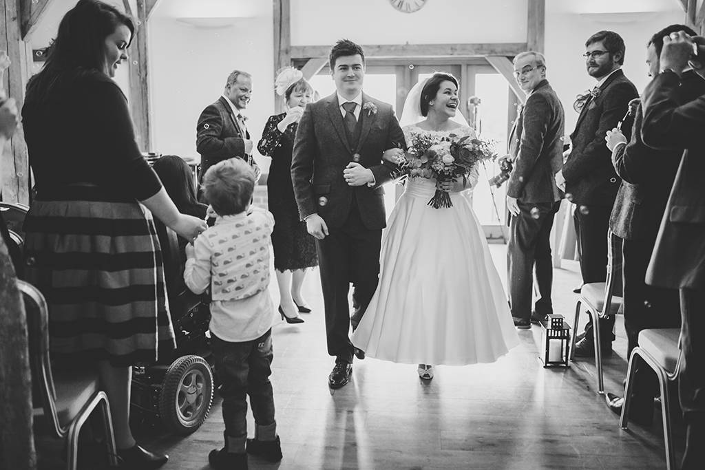 The happy couple walk back down the aisle following their wedding ceremony at Sandhole Oak Barn