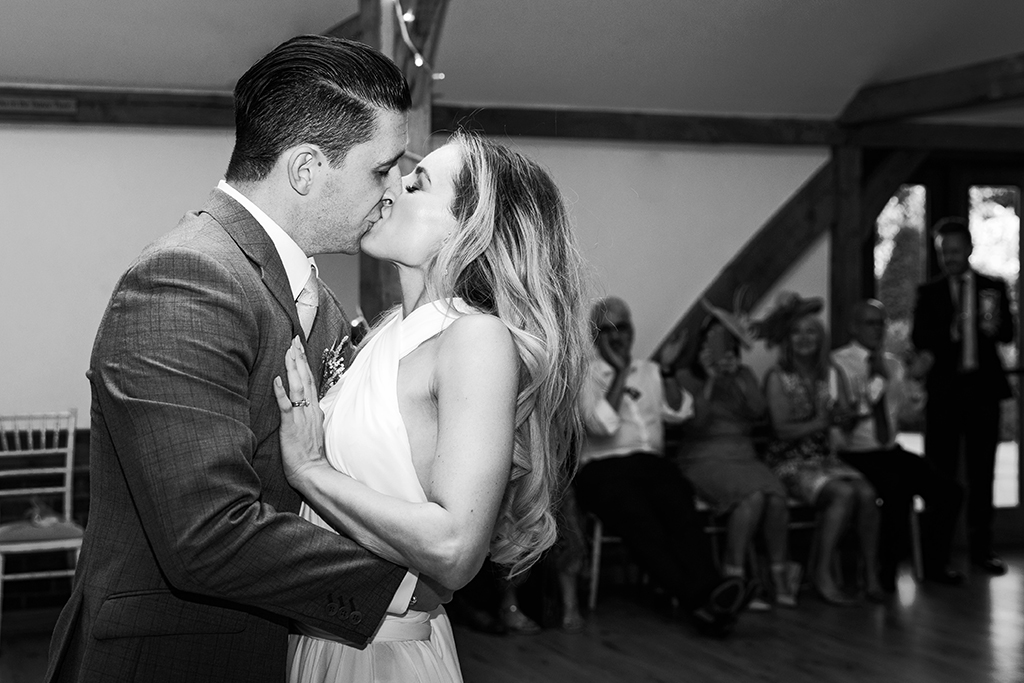 The happy couple share a kiss as they enjoy their first dance at Sandhole Oak Barn In rural Cheshire