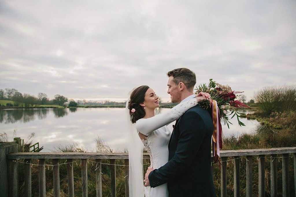 The happy couple pose for a photo by the lake at this rural wedding venue in Cheshire