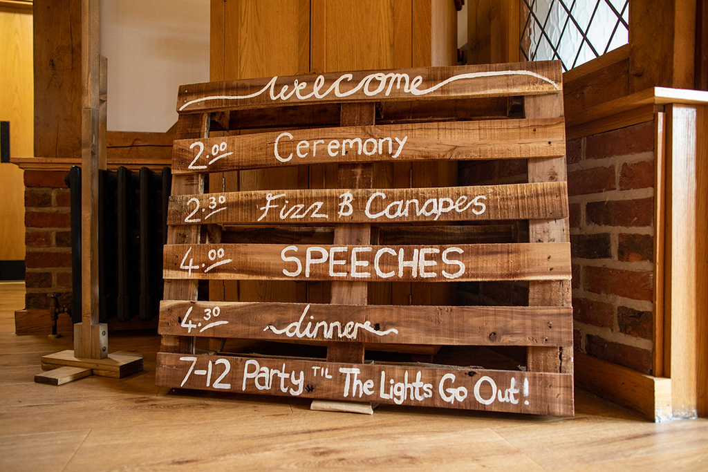 A wooden wedding sign was used for the order of the day at his rustic wedding venue in Cheshire