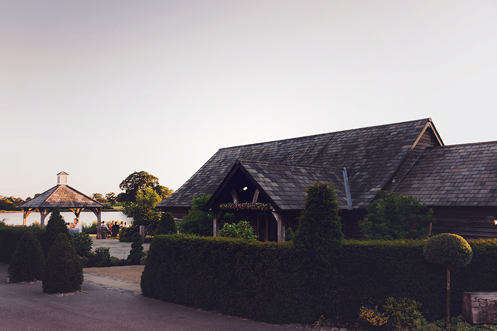 Wedding guests enjoy mingling outside on a summer’s evening at this barn wedding venue in Cheshire