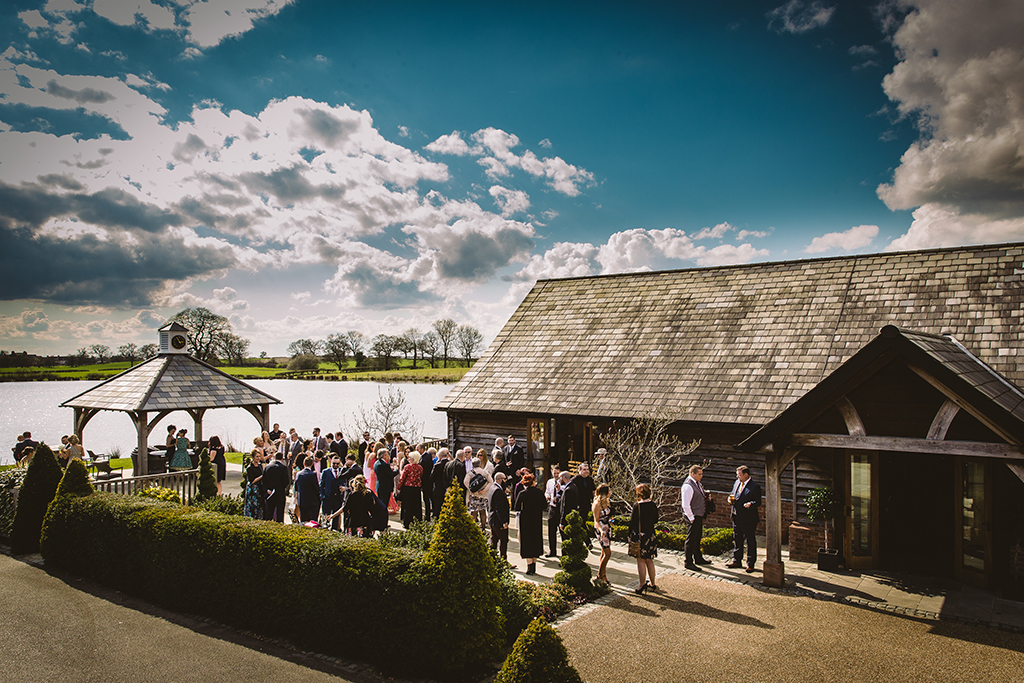 Wedding guests can enjoy the lakeside views as they mingle in the sunshine at this rustic barn wedding venue near Manchester