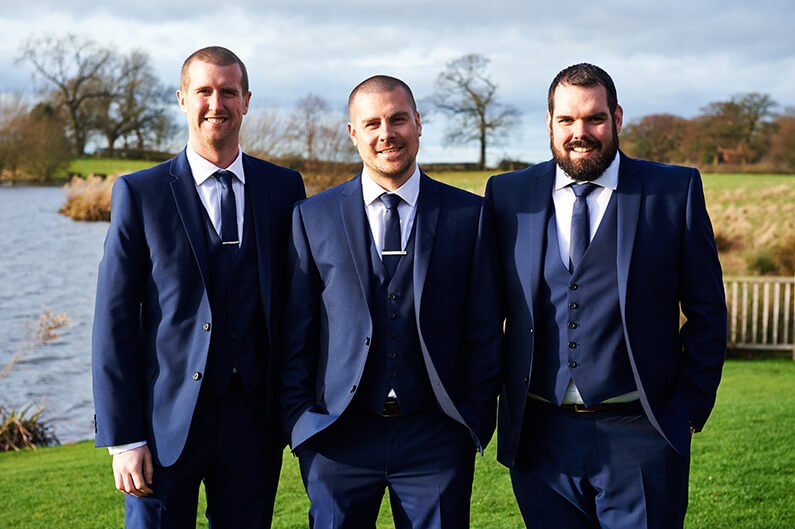 Groom and groomsmen in navy blue suits at Sandhole Oak Barn