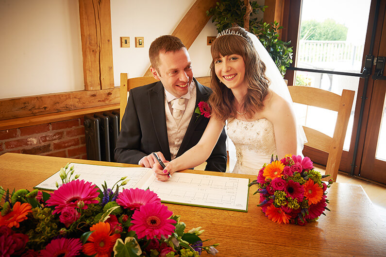 Surrounded by brightly coloured flowers signing the register