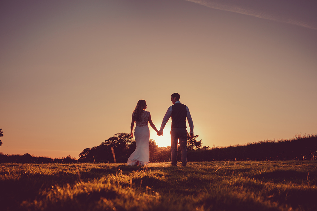 The bride and groom have wedding pictures taken as the sunsets at this beautiful barn venue