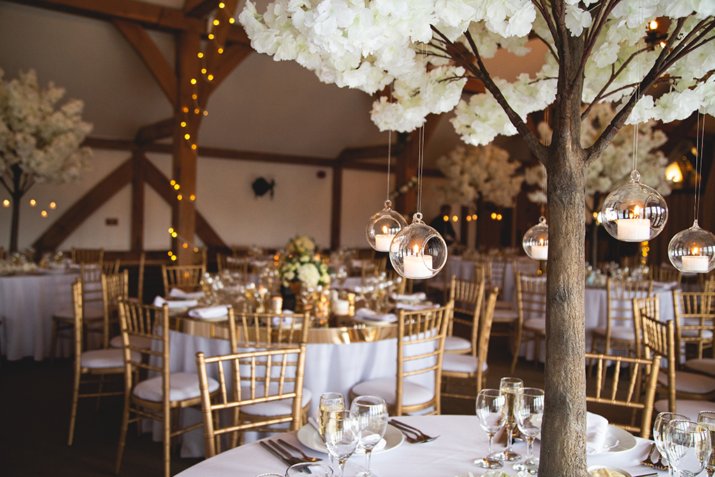 The tables were decorated with miniature blossom trees with hanging candles baubles at Sandhole Oak Barn in Cheshire