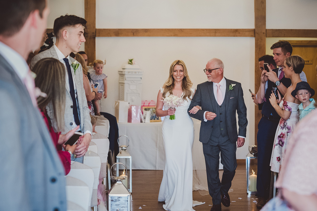 The happy bride-to-be and her father walk down the aisle at this North West barn wedding