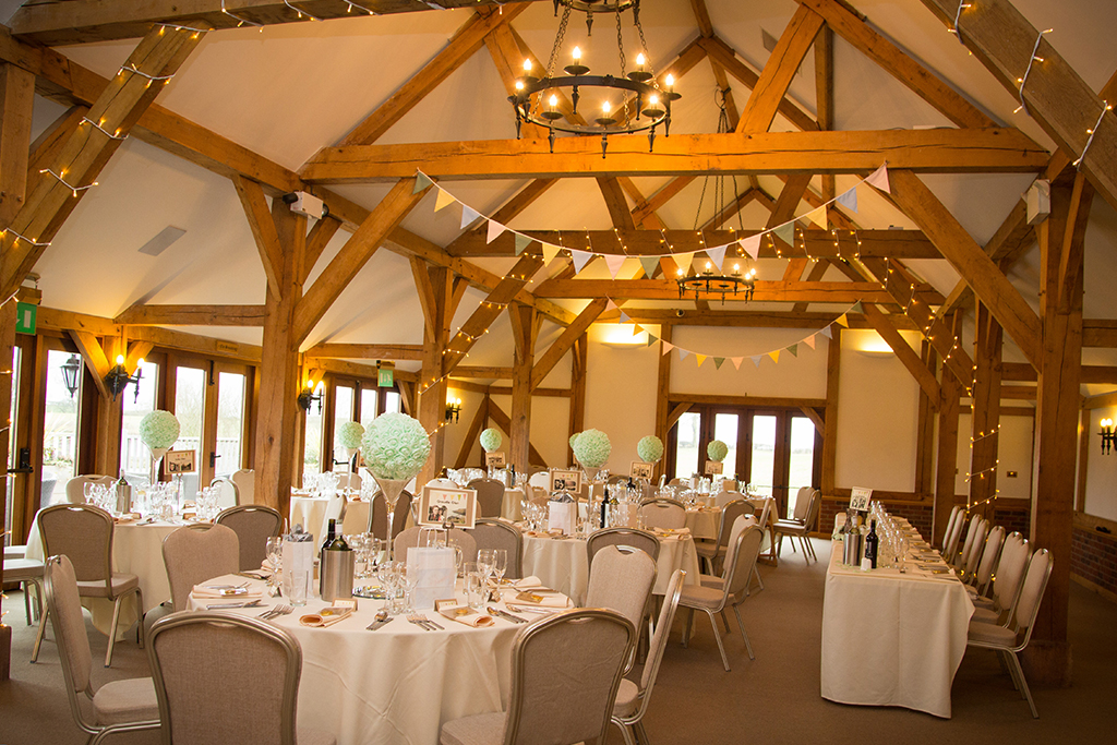 The oak barn decorated with pastel bunting and table decorations with fairy lights along the beams