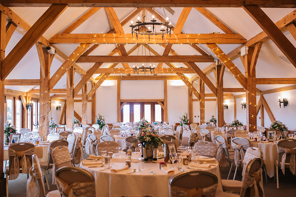 The Oak Barn has was set up for the wedding breakfast with fairy lights and pretty lace sashes on the chair