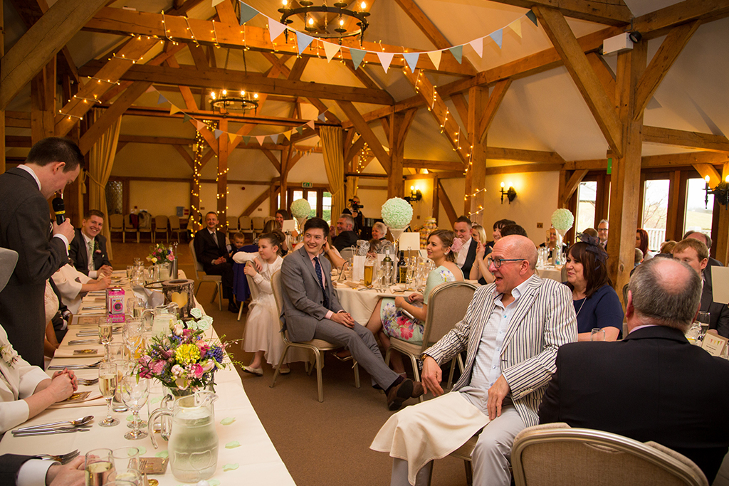 The wedding guests enjoy listening to the groom’s wedding speech at this barn venue in Cheshire