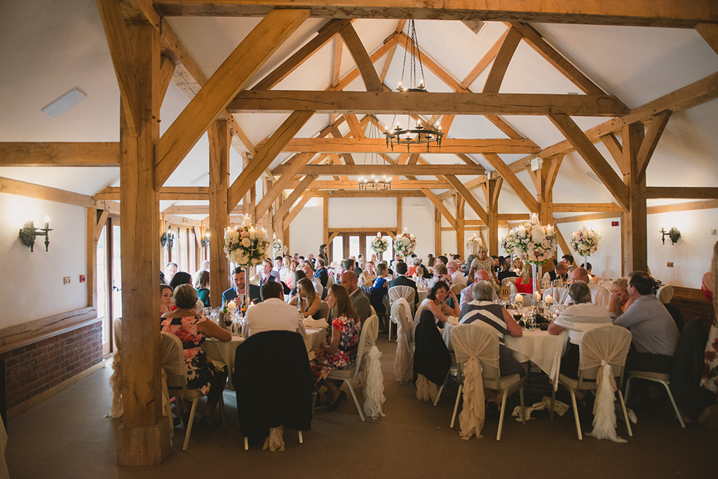 Guests sit down in the stylish Oak Barn to enjoy a delicious wedding breakfast created by the exclusive wedding caterers