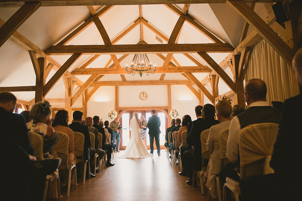The bride and groom exchange wedding vows in the intimate and romantic Oak Barn
