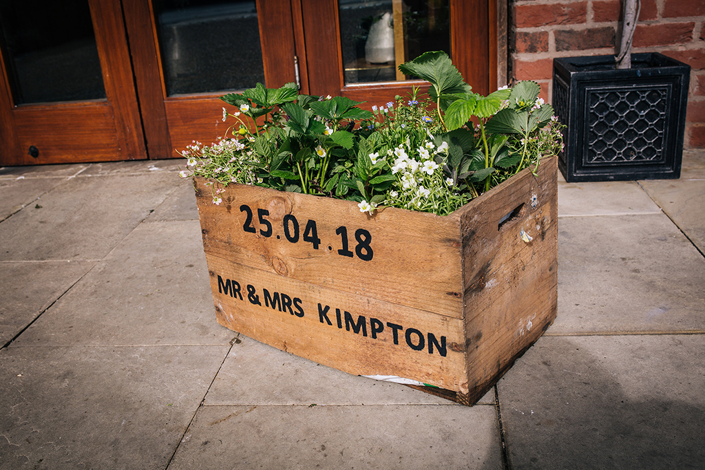 Spring wedding flowers and lush foliage were displayed in a personalised wedding crate at Sandhole Oak Barn