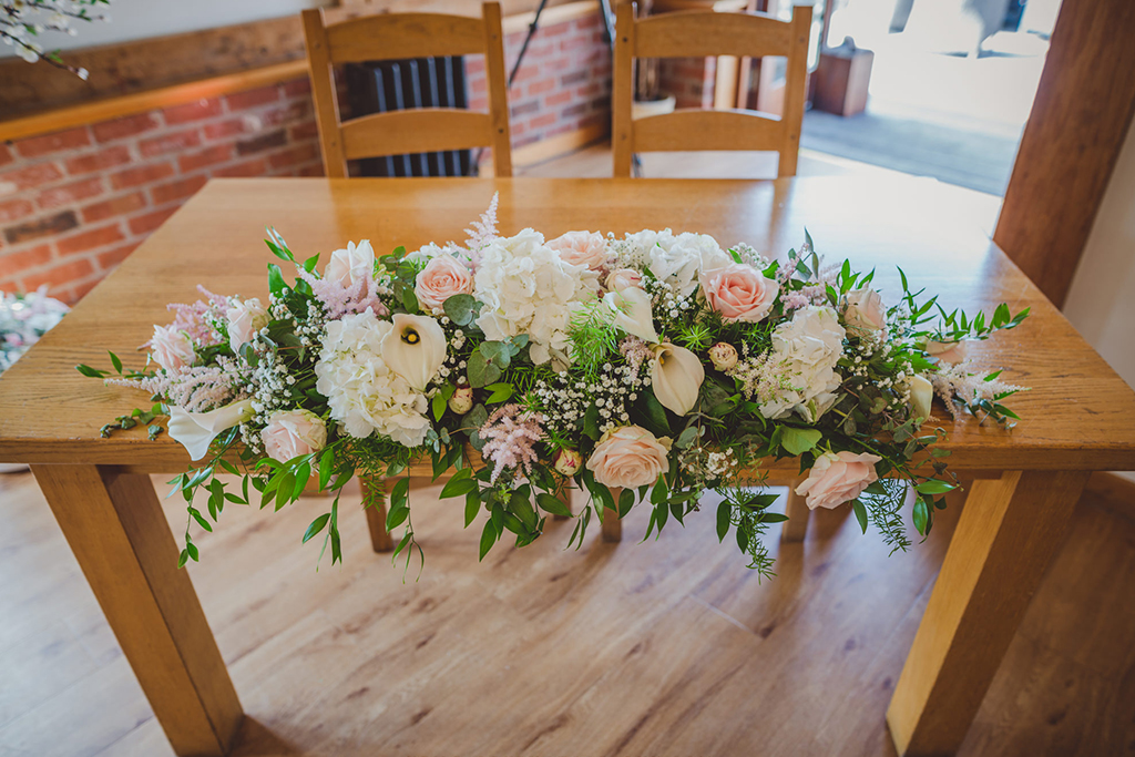 The ceremony table was decorated with an arrangement of delicate pale pink and white wedding flowers and lush green foliage
